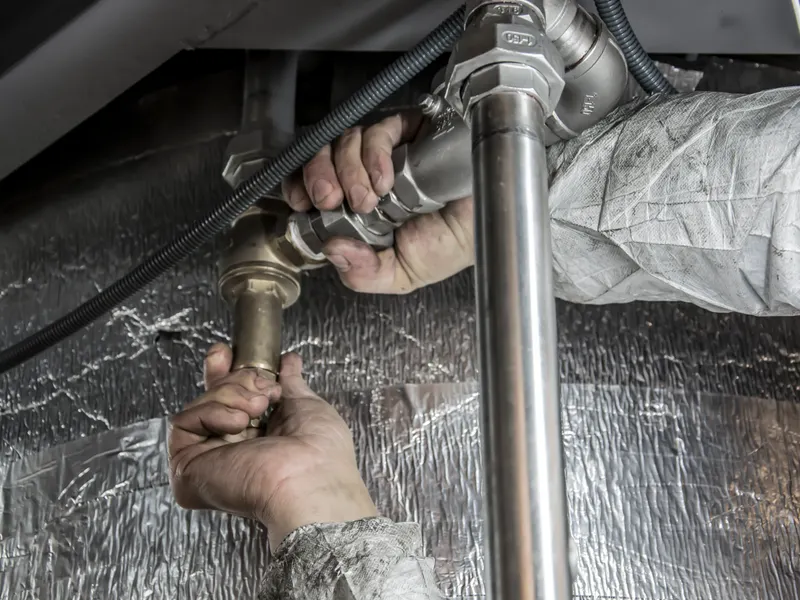 Plumber repairing a copper pipe fitting with a wrench in Noblesville, IN